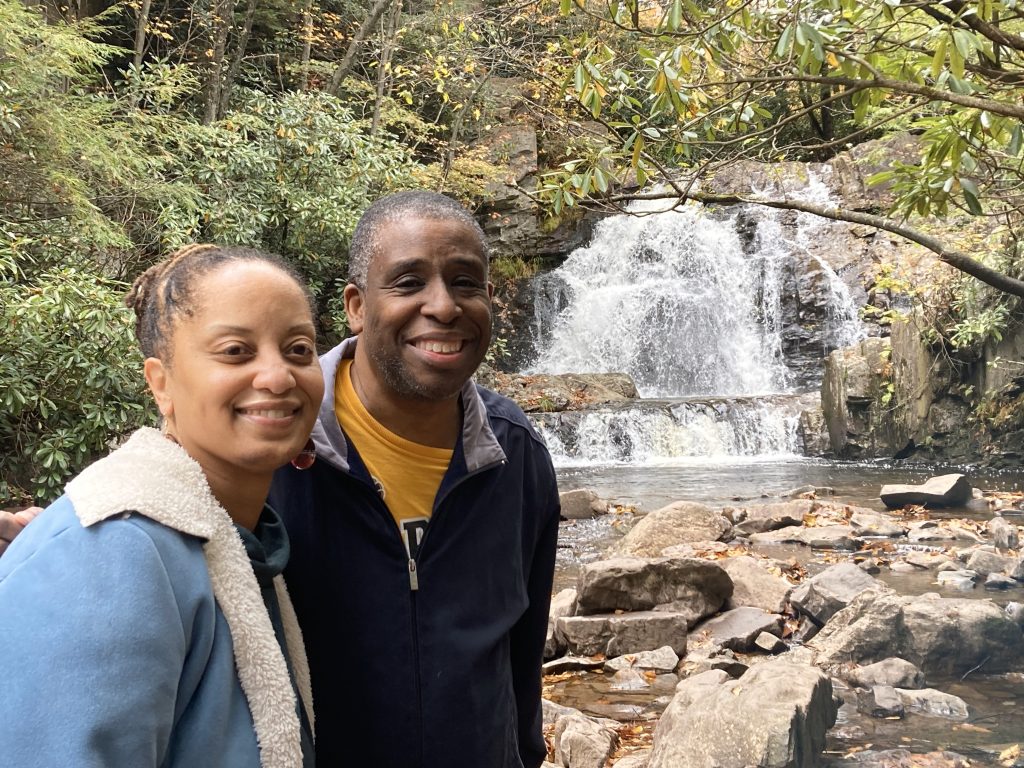 Two individuals in front of a scenic waterfall